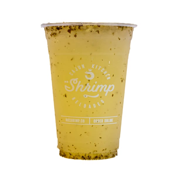 Clear plastic cup of yellow herb-infused shrimp broth labeled Mr Shrimp, photographed against a white background.