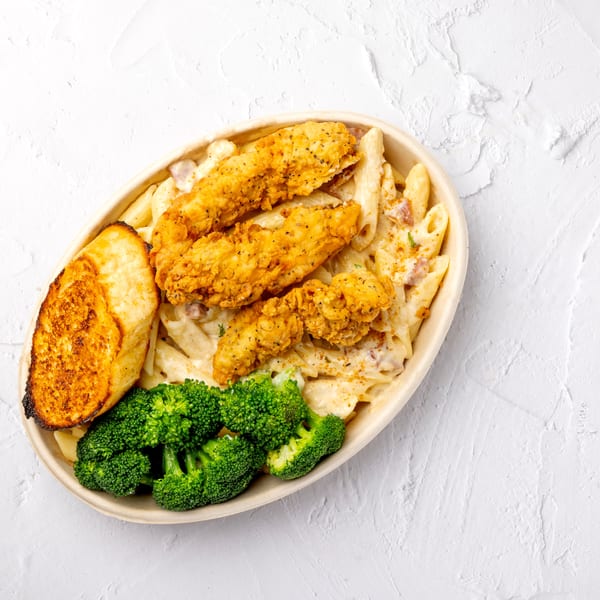 Crispy fried chicken tenders served over creamy penne pasta with broccoli and toasted garlic bread.
